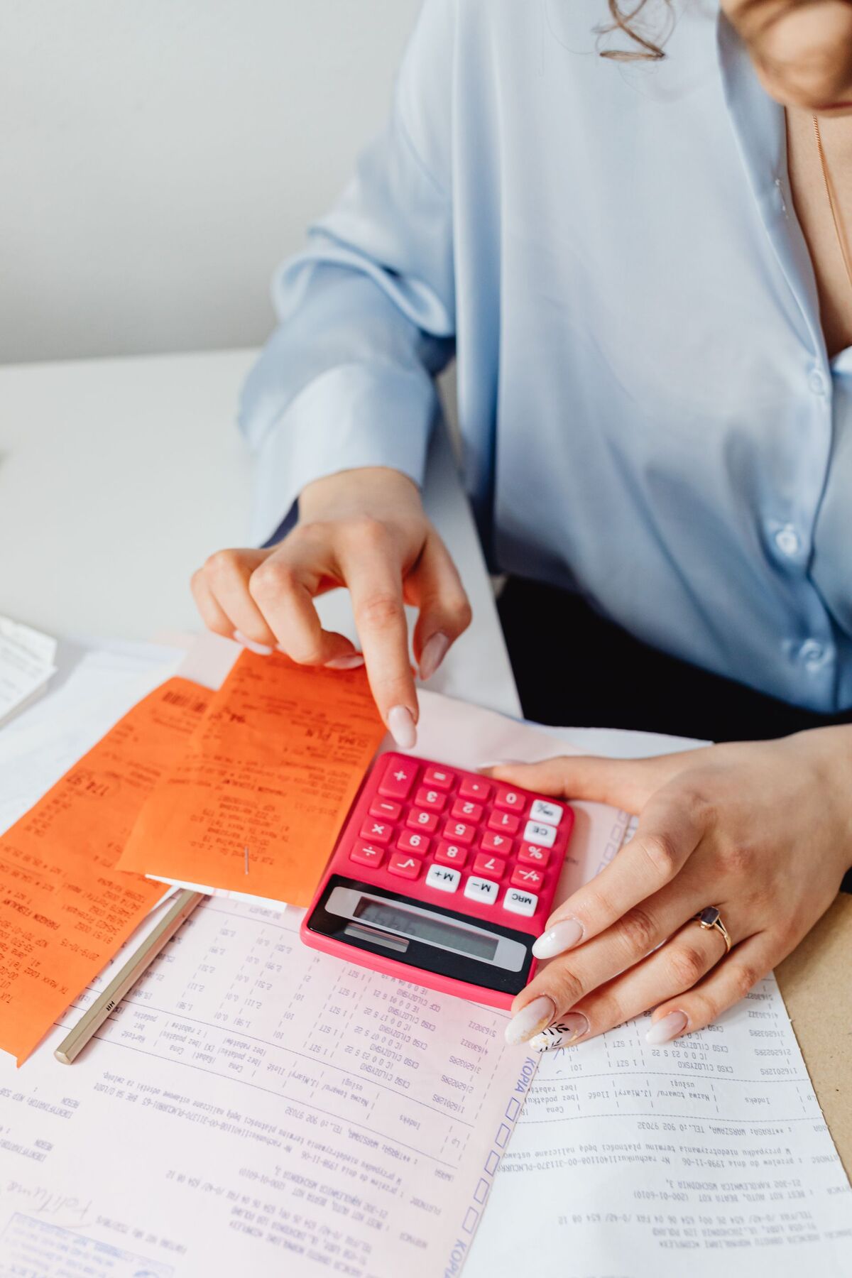 Trabajadora calculando remuneraciones sobre planillas y comprobantes