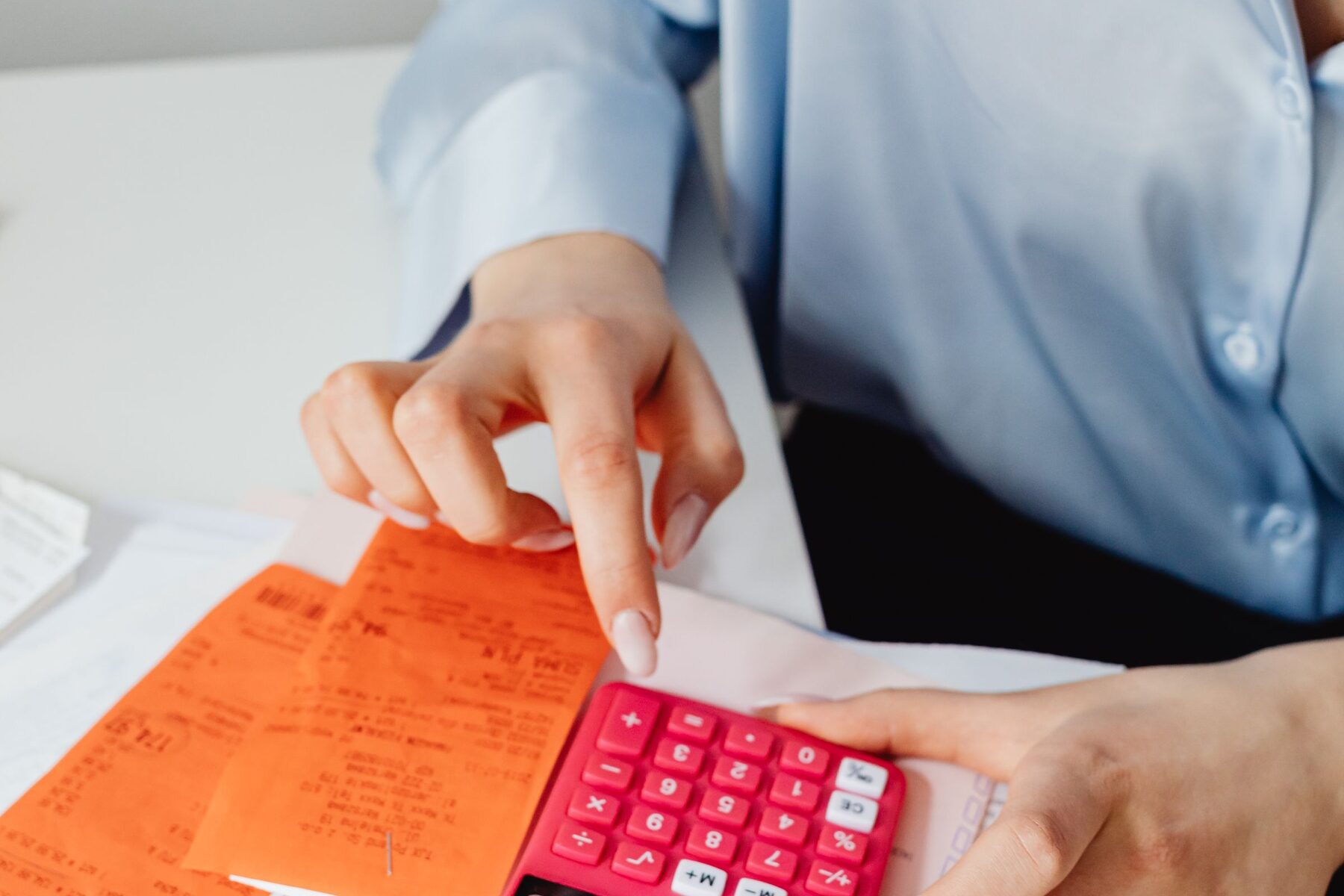 Persona calculando remuneraciones con una calculadora y comprobantes